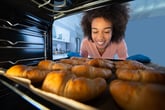 Happy woman baking croissants in her oven