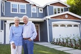 Senior couple standing in front of their home