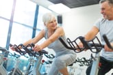 senior couple on exercise bikes at gym