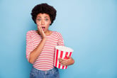 Shocked woman with tub of popcorn