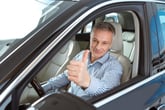 Happy man smiling and giving a thumbs up in a new car