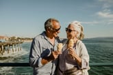 Happy senior couple eating ice cream on a sunny day with sunglasses on the Santa Monica Pier in California
