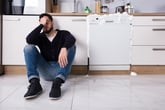 Upset man with overloaded dishwasher leaking suds