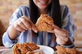 Woman eating fried chicken at a restaurant