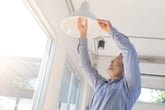 Man adding a light fixture and light bulb to his home
