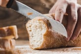 Loaf of bread being sliced by a knife