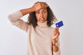 Shocked woman holding a credit card