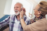happy couple adjusting hearing aids