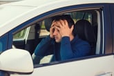 Man driver in car upset or worried about gas prices or insurance