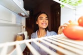 Happy woman looking into a refrigerator