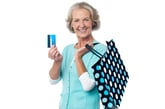 Happy older woman smiling with reusable shopping bag holding a gift card or credit card