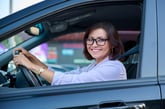 Happy female driver or woman driving a car