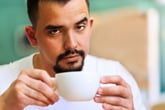 Man drinking coffee eyebrows raised