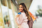 Happy woman shopping with credit card in cool weather clothes in autumn
