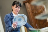 Woman looking at the back of antique china plate dishware
