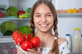 Girl with tomatoes in front of fridge