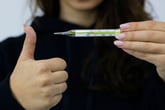 Person holding a glass thermometer