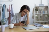 Stressed woman dealing with a phone scam on her smartphone