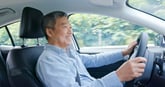 Smiling senior driver in a car on the highway driving for Uber or carrying a passenger