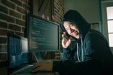 Hacker on the phone and computer using stolen data