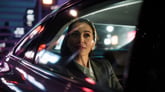 Young businesswoman in a car at night with neon urban lights