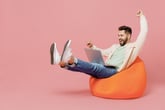 excited man sitting on beanbag looking at computer
