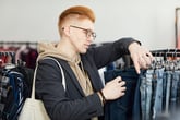 Man browsing jeans and clothing in a vintage thrift shop