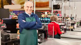 Happy senior working as a grocery cashier at a supermarket checkout