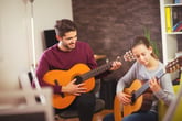 Man teaching girl to play guitar, father and daughter playing music together