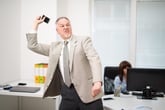 Angry man in the office throwing his phone