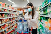 Woman stocking up on water and wearing a face mask at the grocery store