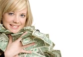 Happy woman hugging lots of dollar bills in a huge pile of money