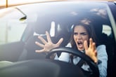 Stressed woman driver panicked and not holding steering wheel while shouting or screaming angrily