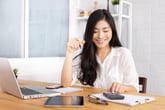 Smiling woman with a calculator and a laptop planning finances or investment strategy