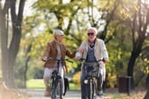 Happy senior couple biking in the park on bicycles outdoors