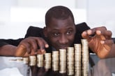 A man counting money in the form of stacks of coins