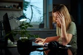 Stressed woman working from home late into the evening and suffering from burnout at her computer desk