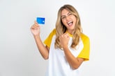 Excited woman with credit card in a victorious or celebratory pose for a debt paid off or a perfect credit score