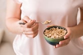Woman eating a bowl of cheerios cereal.