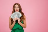 Woman happily fanning out dollar bills.