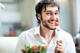 Man eating salad and tomato