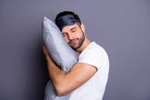 A sleepy man holding a pillow.