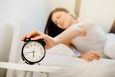 Woman shutting off her alarm clock