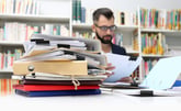 Man at desk with piles of paperwork