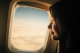 A passenger looking out the window of an airplane.