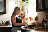 Woman cooking and looking at her smartphone