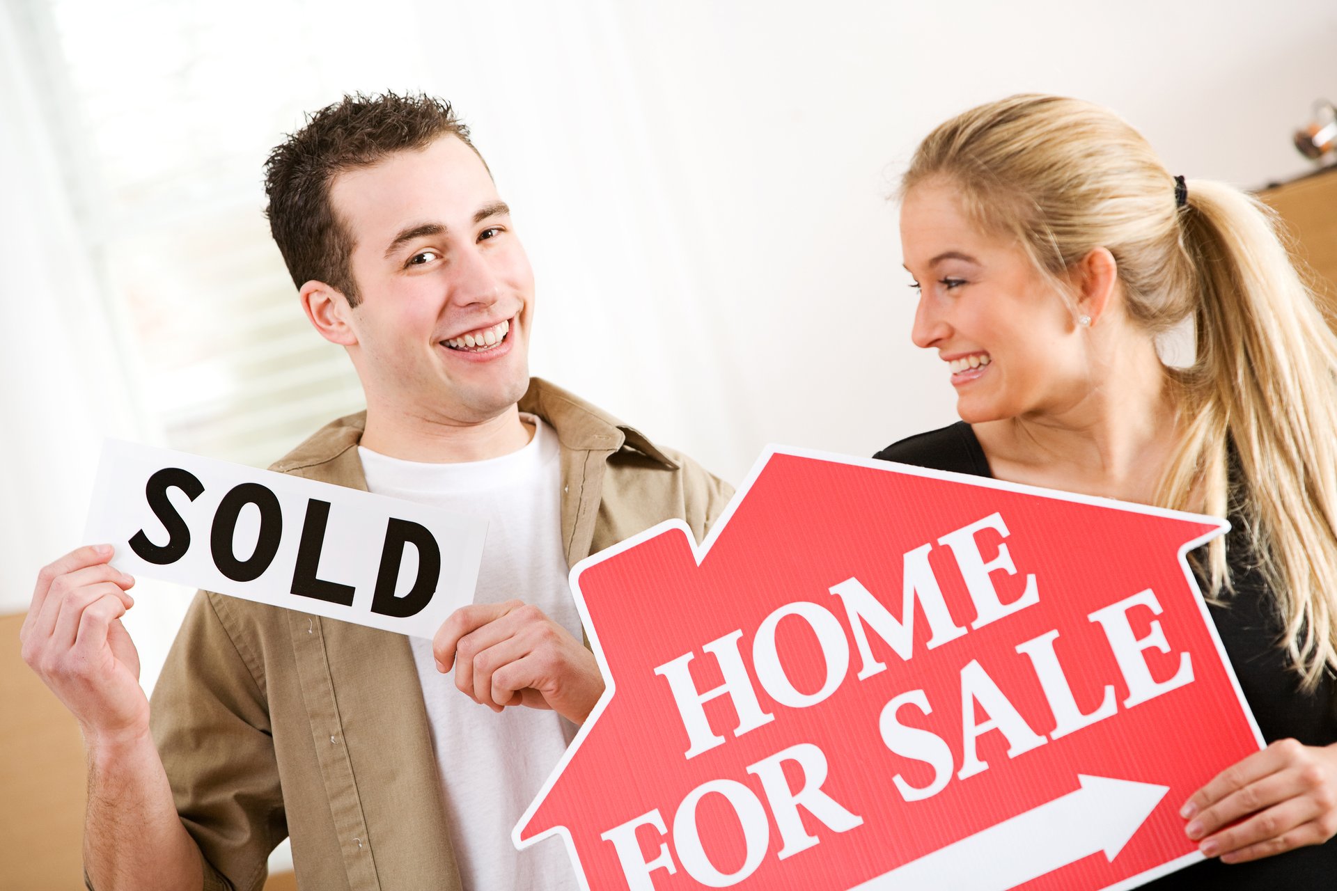 Couple with sold and home for sale signs