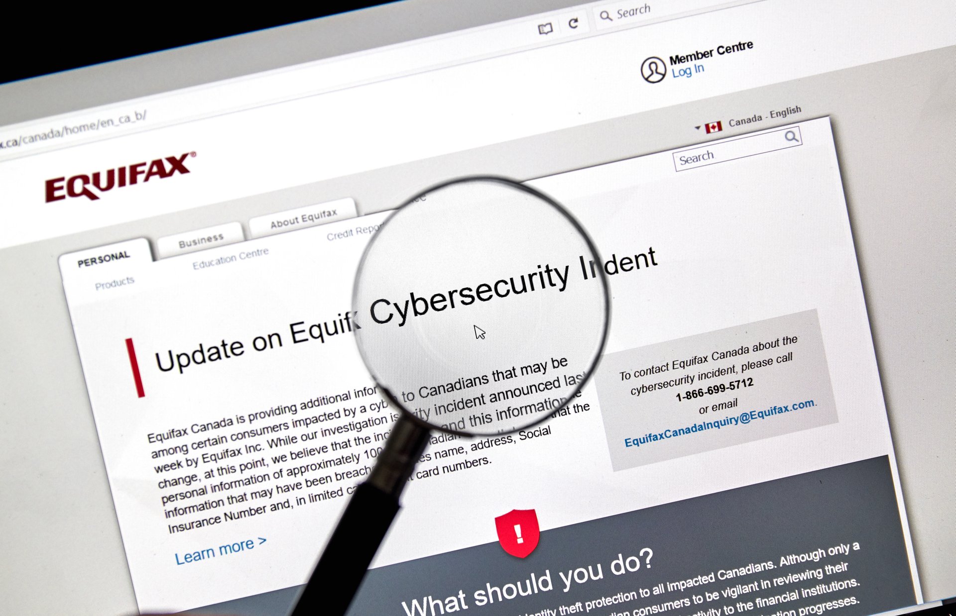 Magnifying glass and Equifax security breach alert online.