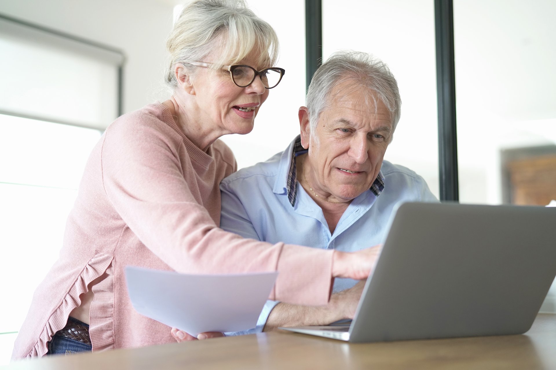 A senior couple reviews their finances on a laptop computer