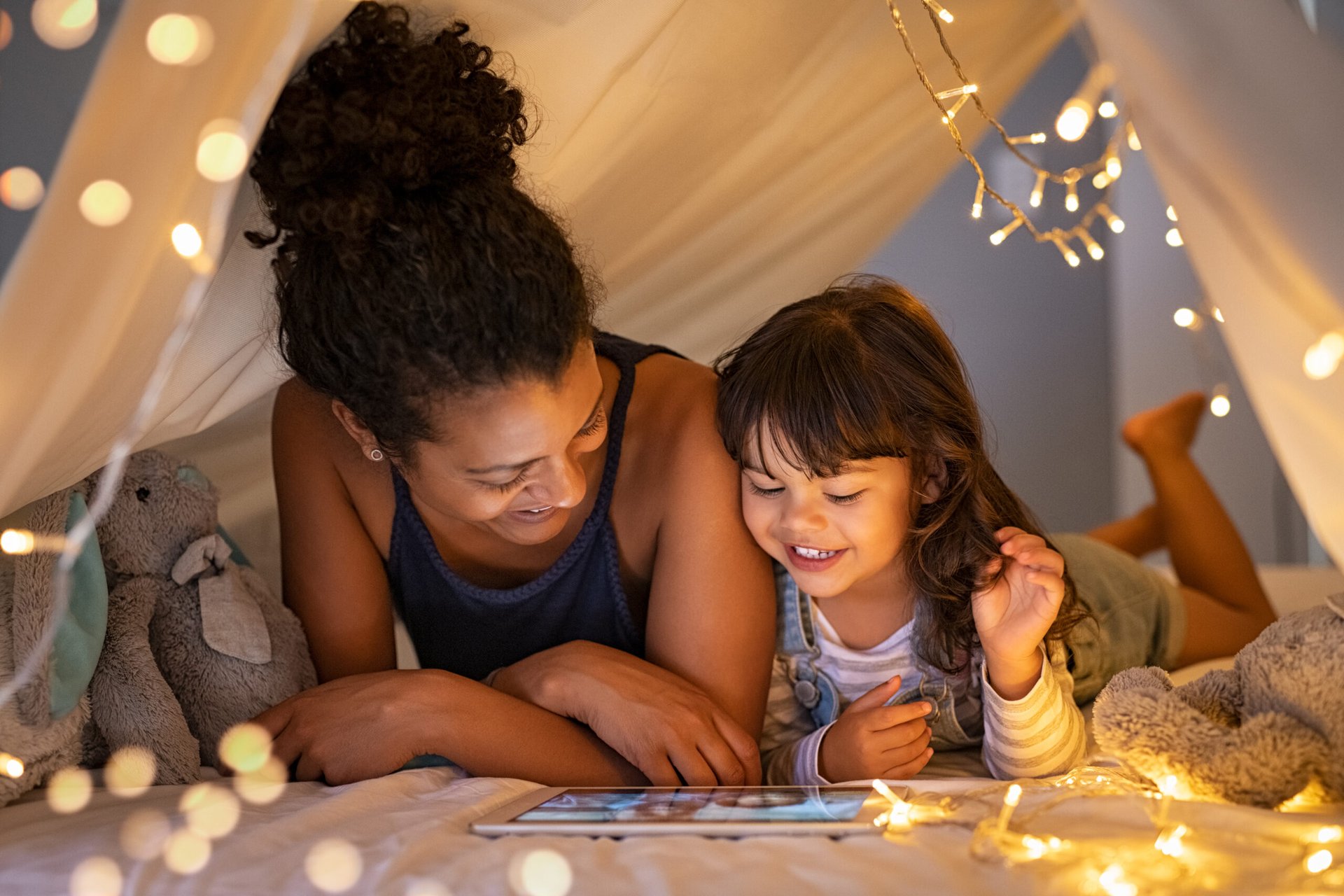 Mother and daughter playing on a tablet in a tent